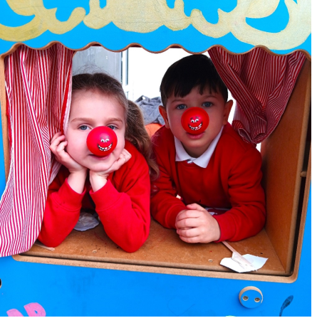 A child and child with red nose on a puppet theater

Description automatically generated