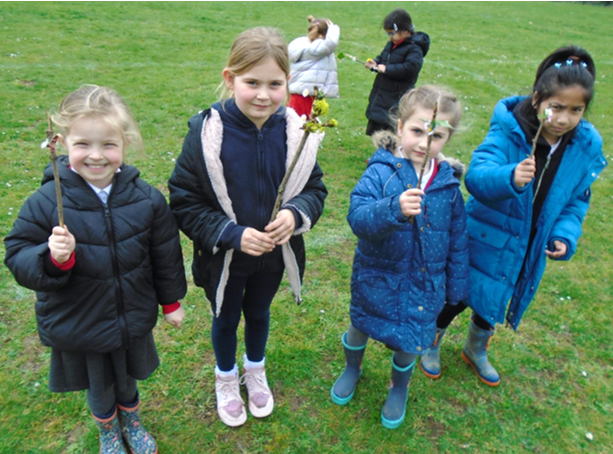 A group of children standing in a field holding sticks

Description automatically generated