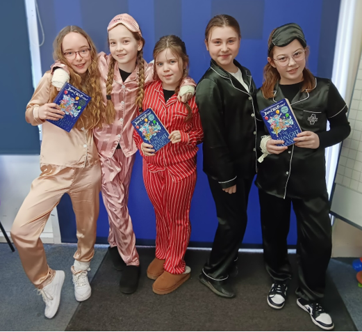 A group of girls in pajamas holding books

Description automatically generated