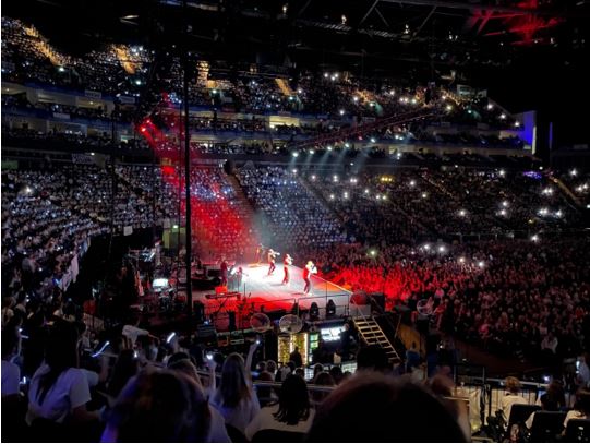 A group of people performing on stage in a stadium

Description automatically generated