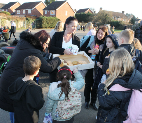 A group of people standing around a box of food

Description automatically generated