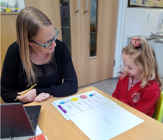 A person and a child sitting at a table with papers

Description automatically generated