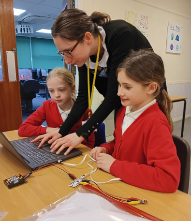 A person and two girls using a computer

Description automatically generated