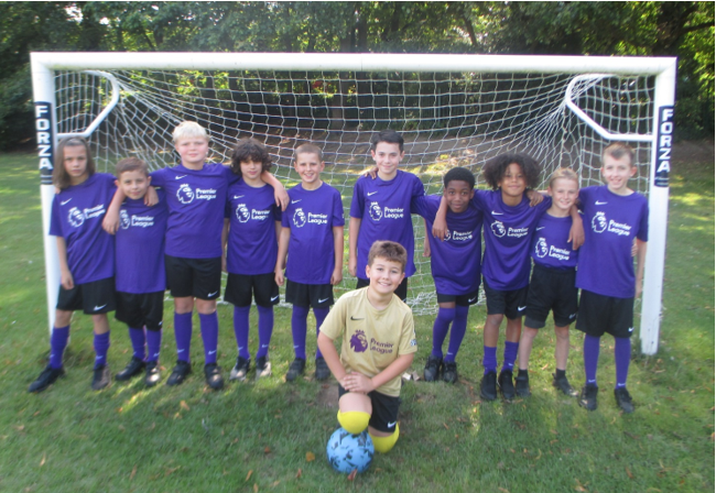 A group of kids in purple uniforms standing in front of a goal

Description automatically generated