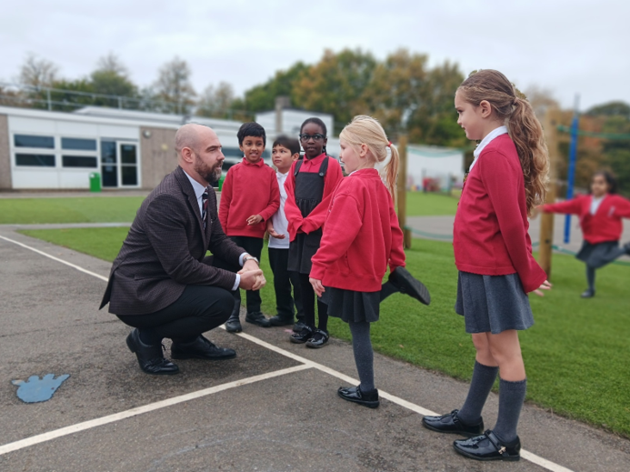 A person kneeling in front of a group of children

Description automatically generated